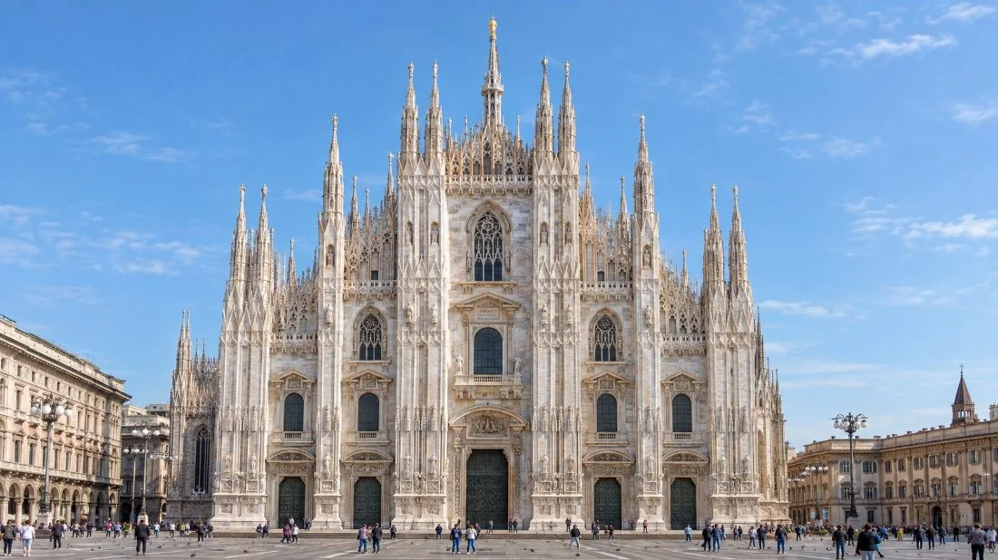 La façade en marbre du Duomo di Milano avec ses cinq portes en bronze et ses statues, vue depuis la Piazza del Duomo à la lumière du matin