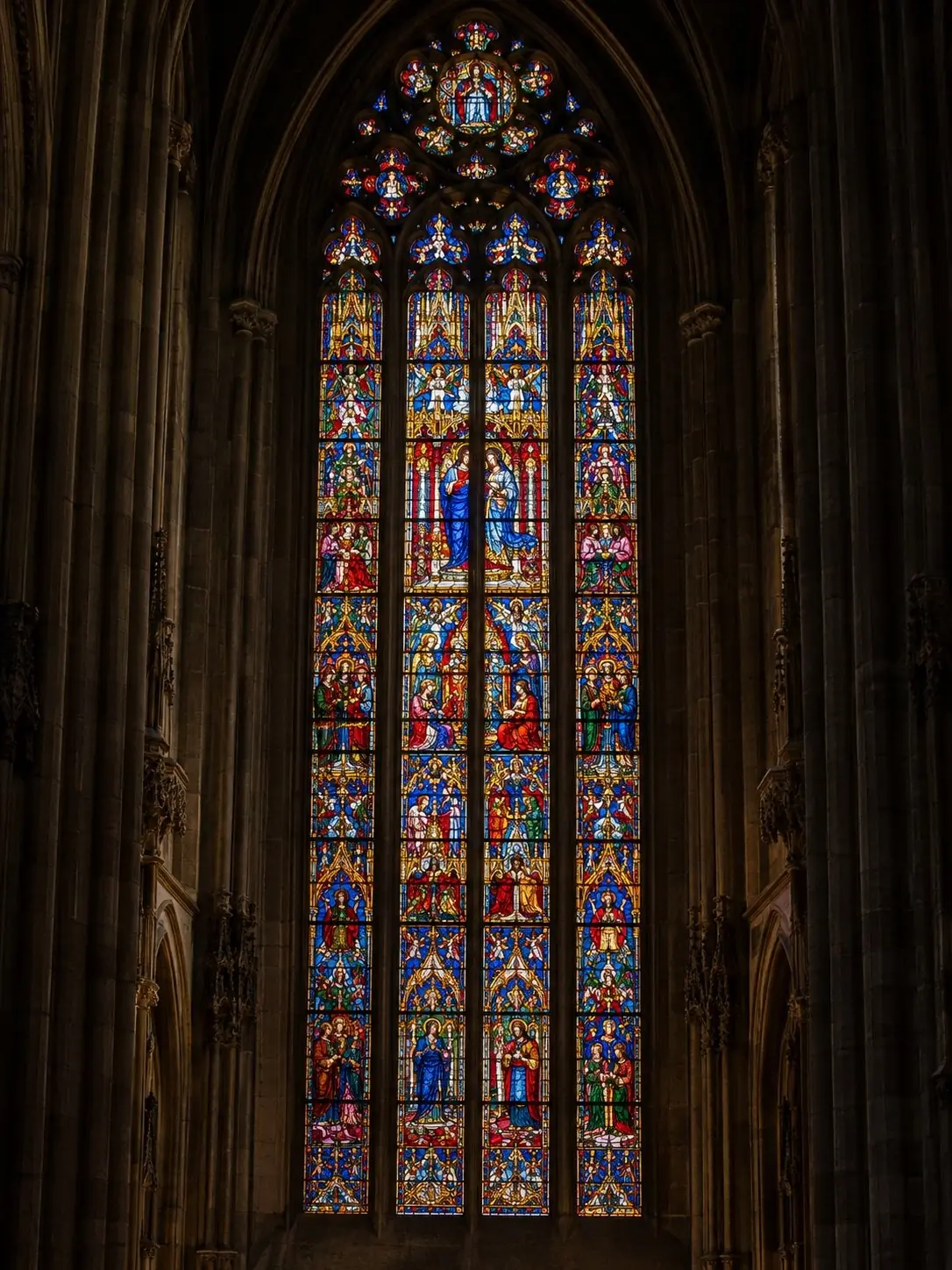 Une vitrail monumental de l'abside du Duomo di Milano rayonnant de rouge, de bleu et d'or